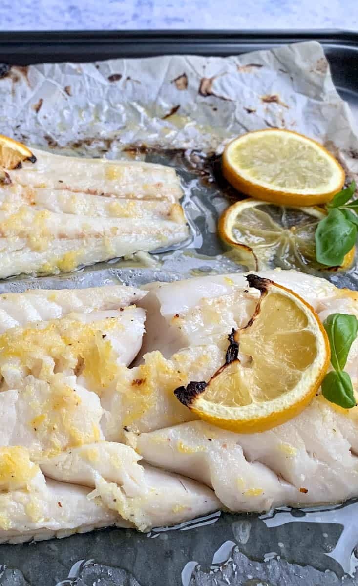 flaky white fish baked with lemon slices and basil leaves