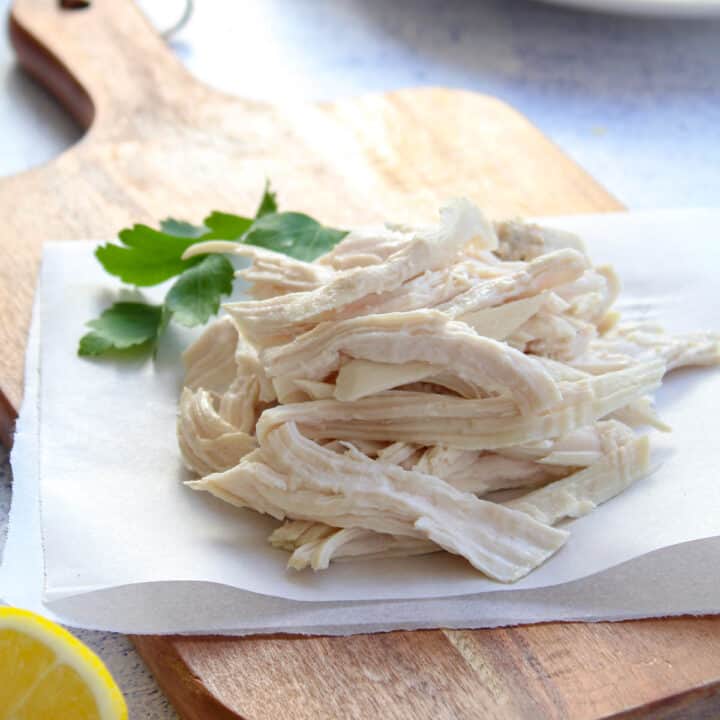 shredded poached chicken on a chopping board