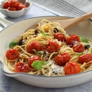 Spaghetti with roasted cherry tomatoes served with parmesan and basil leaves