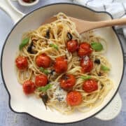 roasted cherry tomatoes on pasta served with parmesan cheese and fresh basil leaves
