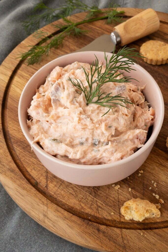 Smoked salmon dip in a pink bowl on the wooden chop board