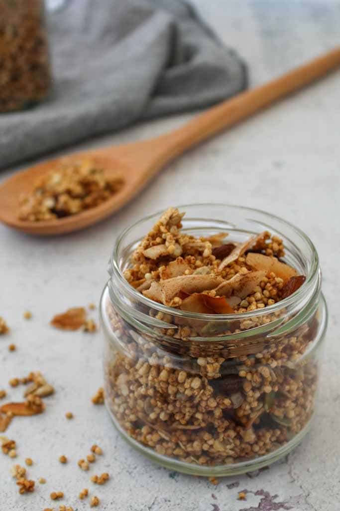 Granola with toasted coconut in a glass jar and wooden spoon