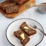 Two pieces of banana bread with butter on a round plate Pinterest image