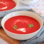 a bowl with red lentil and beetroot soup garnished with yogurt and greens