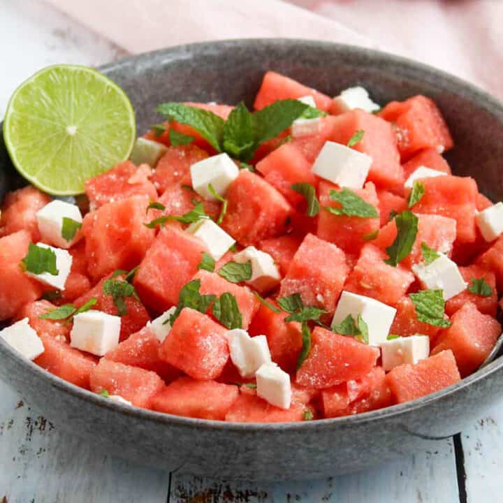 watermelon salad with feta cubes and fresh mint leaves in a grey serving bowl