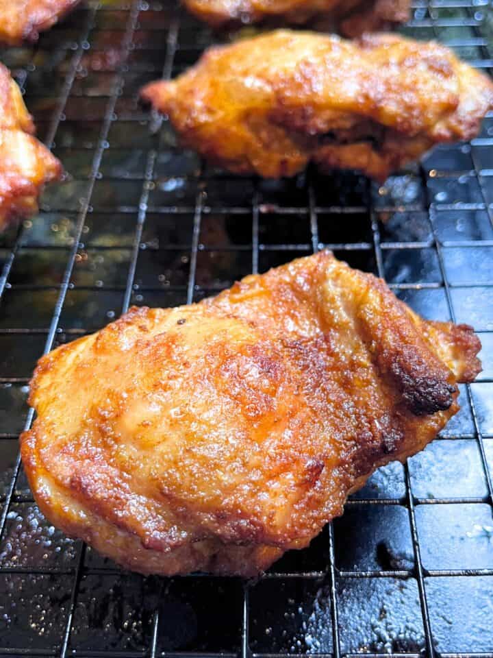 A piece of seasoned, crispy baked chicken sits on a wire rack, with more pieces visible in the background—perfectly capturing the essence of a delicious Middle Eastern Chicken Shawarma recipe.