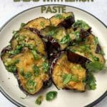 roasted eggplant slices on a plate with chopped coriander