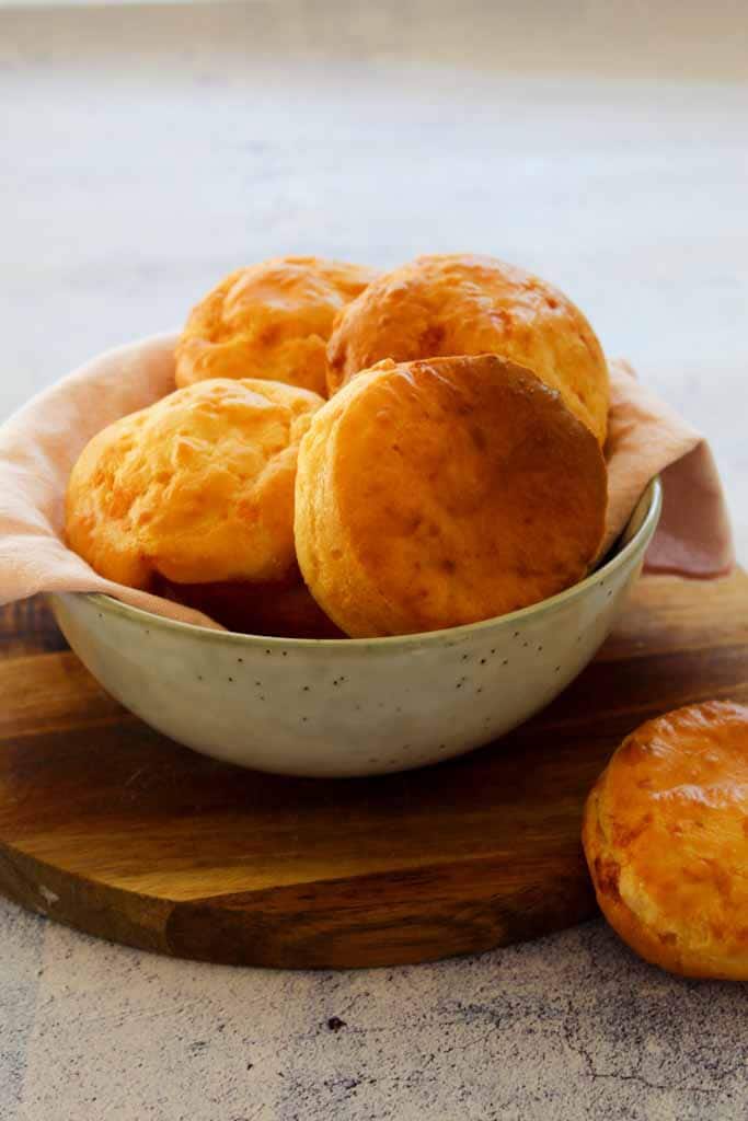 brazilian cheese bread rolls in a round bowl on a wooden board
