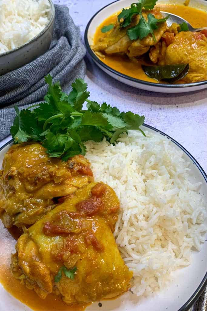 chicken in madras sauce on a plate with basmati rice and fresh coriander leaves