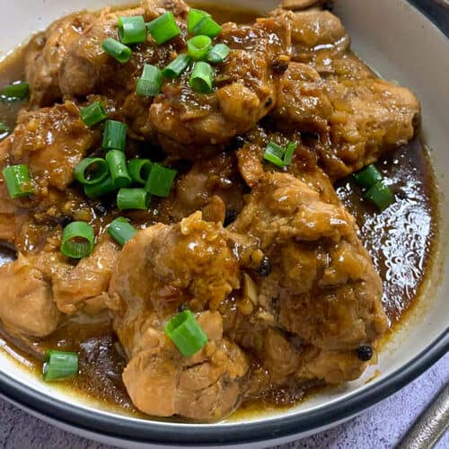 Filipino adobo chicken thighs in a rich sauce served with green onions
