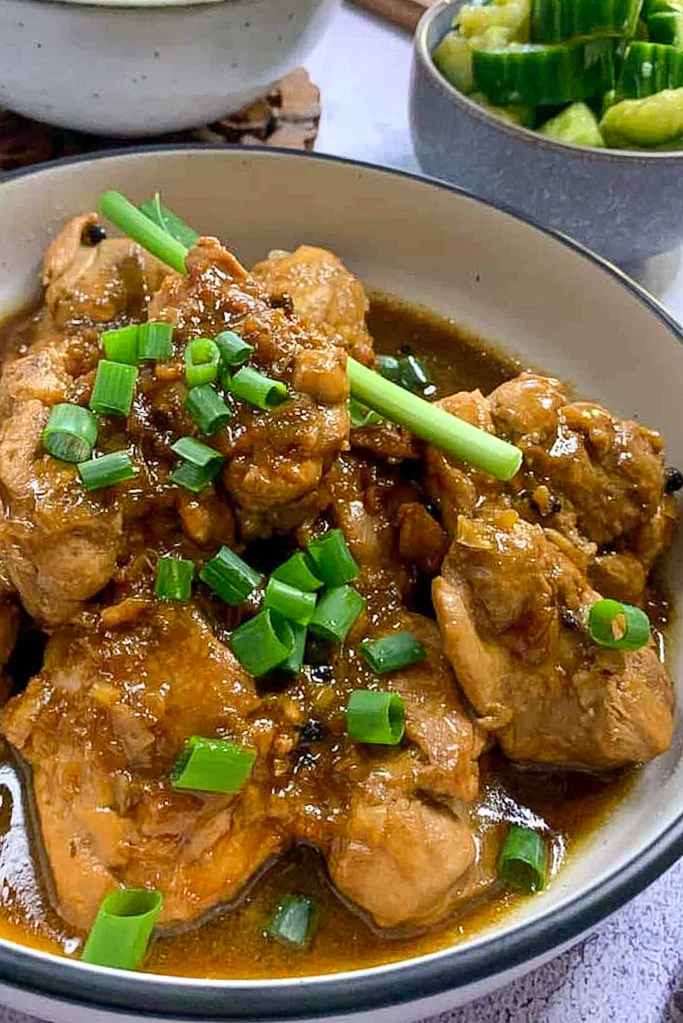 adobo chicken thighs in rich sauce served with green onions