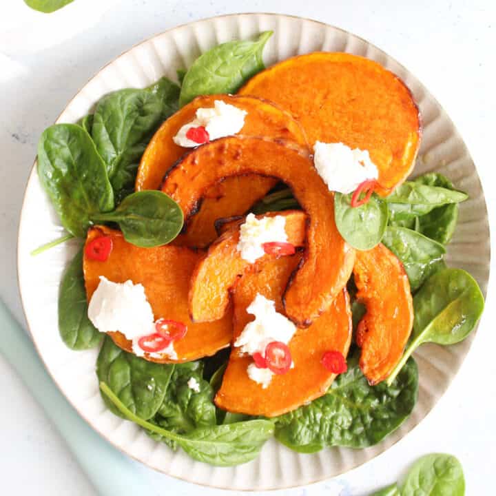 roasted butternut squash slices on a bed of baby spinach topped with goats cheese