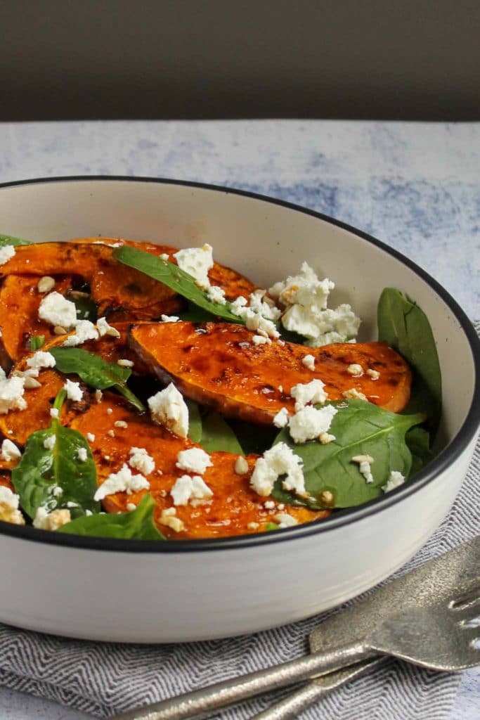 roasted pumpkin with feta cheese and baby spinach in a white plate