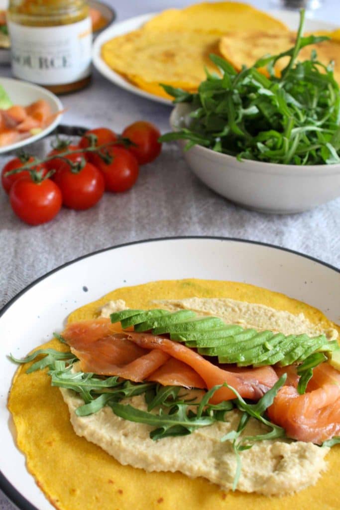 golden carrot crepes with humus and salmon on a set breakfast table