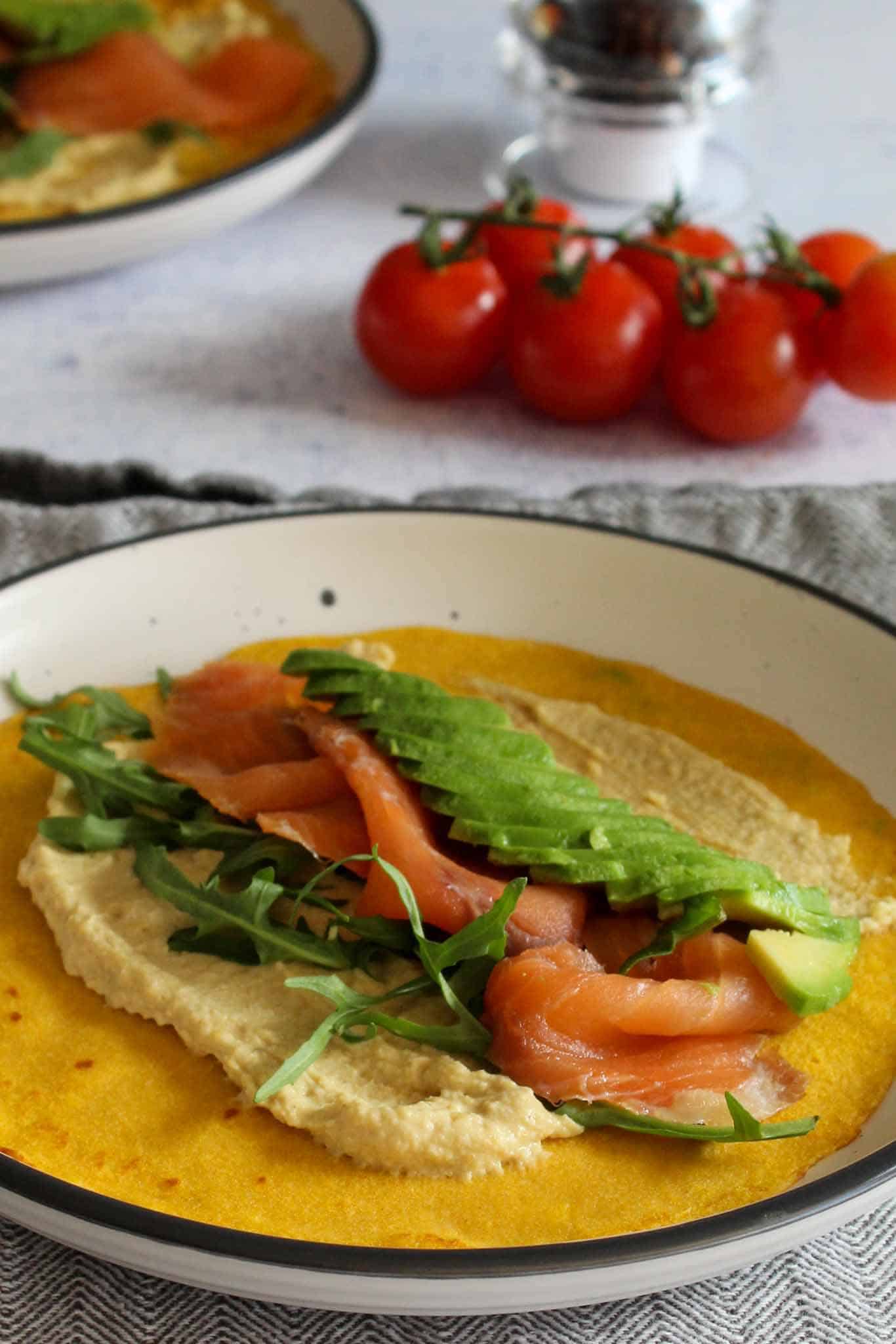 carrot crepes with hummus and salmon on a white plate
