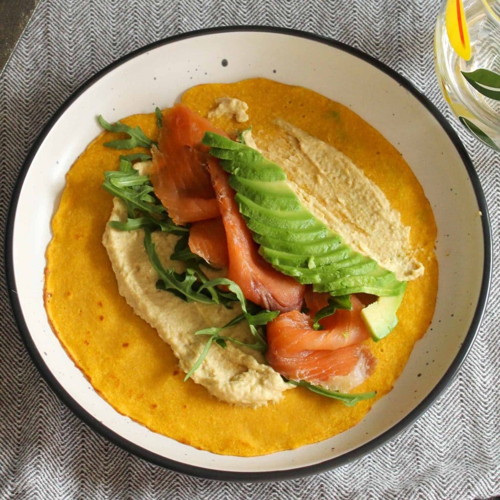 yellow carrot crepe with hummus and salmon, shot from above
