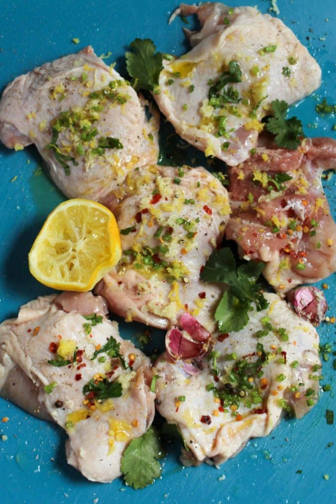chicken thighs in lemon and garlic marinade on a blue chopping board