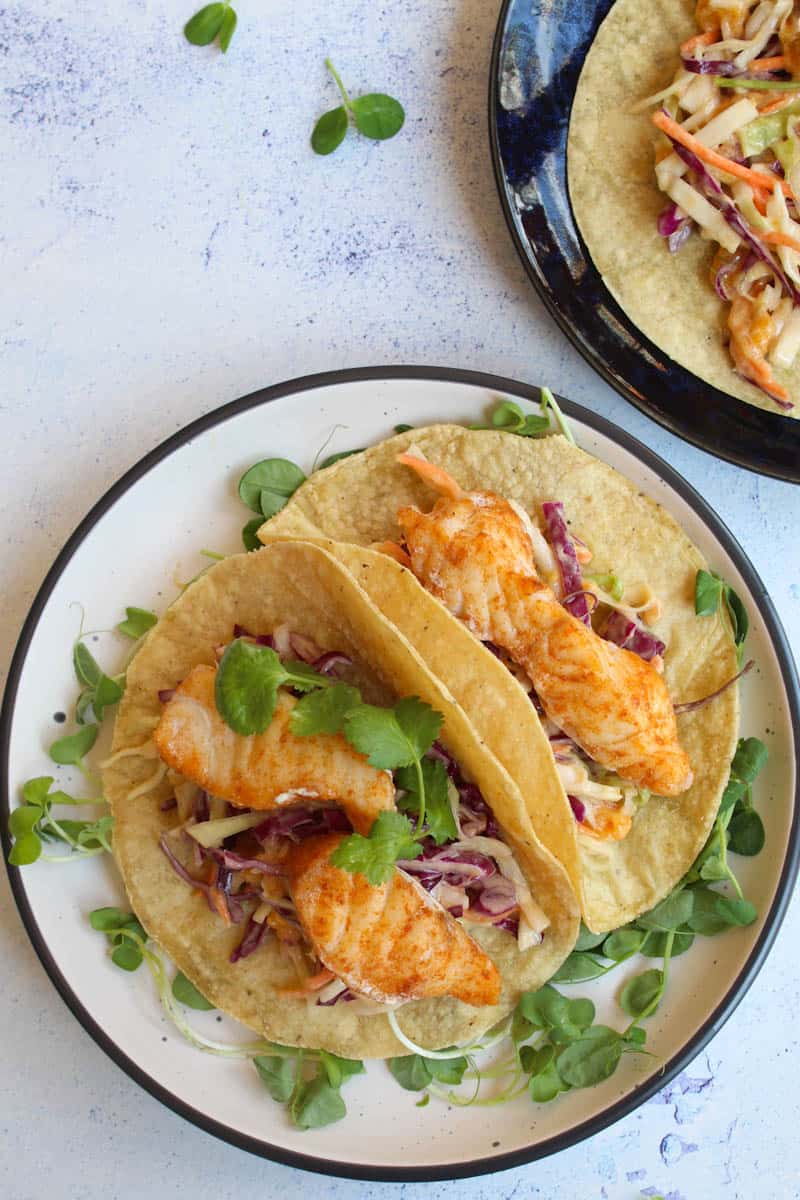two fish tacos with slaw on a plate