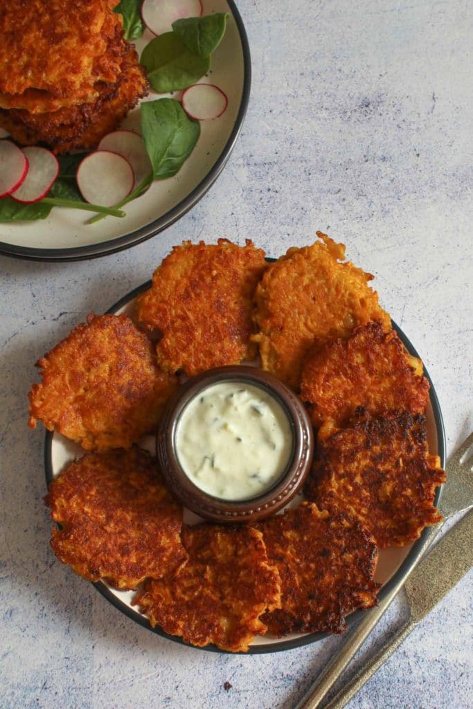 sweet poatato and haloumi fritters on a round plate with tzatziki sauce in the middle