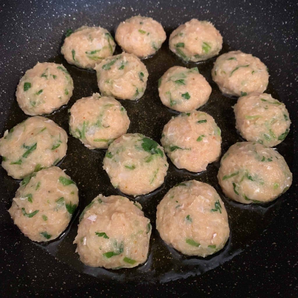 raw Thai fish cakes in a frying pan