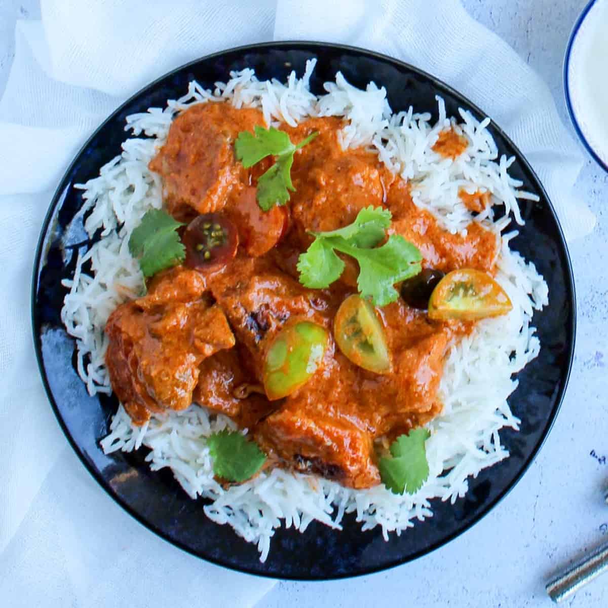 healthy butter chicken served over basmati rice with cherry tomatoes