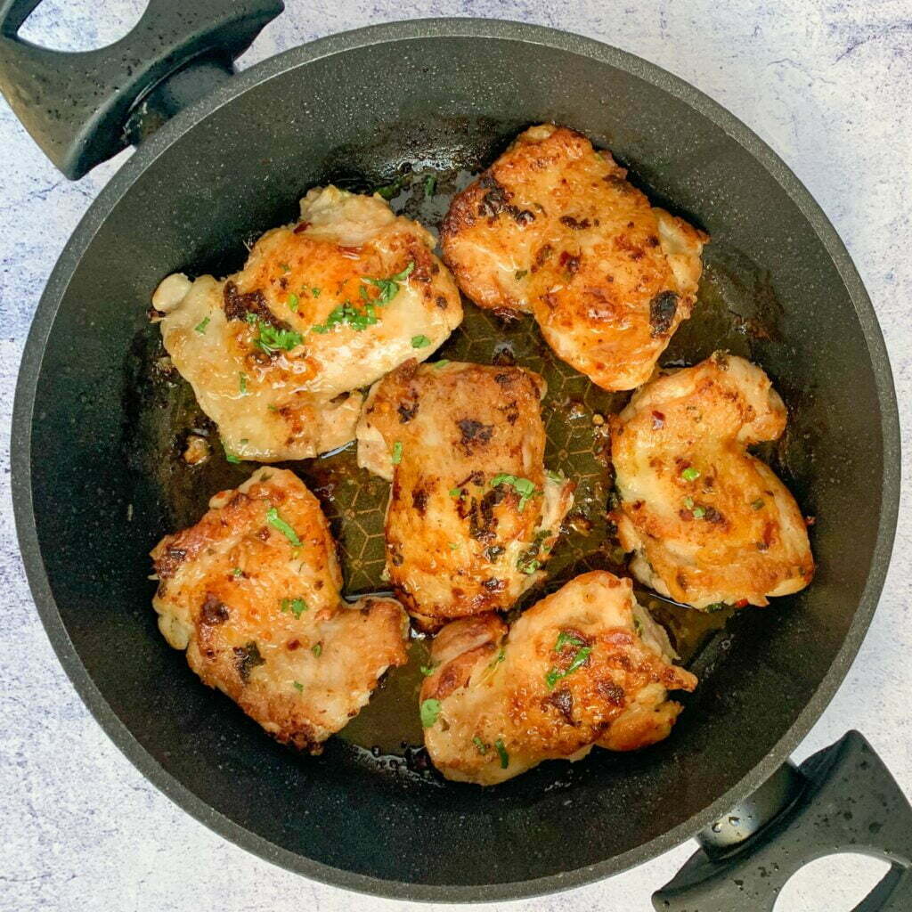 6 golden fried lemon and garlic chicken thighs in a frying pan