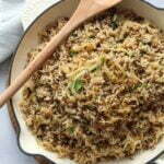 Spiced Rice & Lentils Mejadra in a white frying pan with a wooden spoon