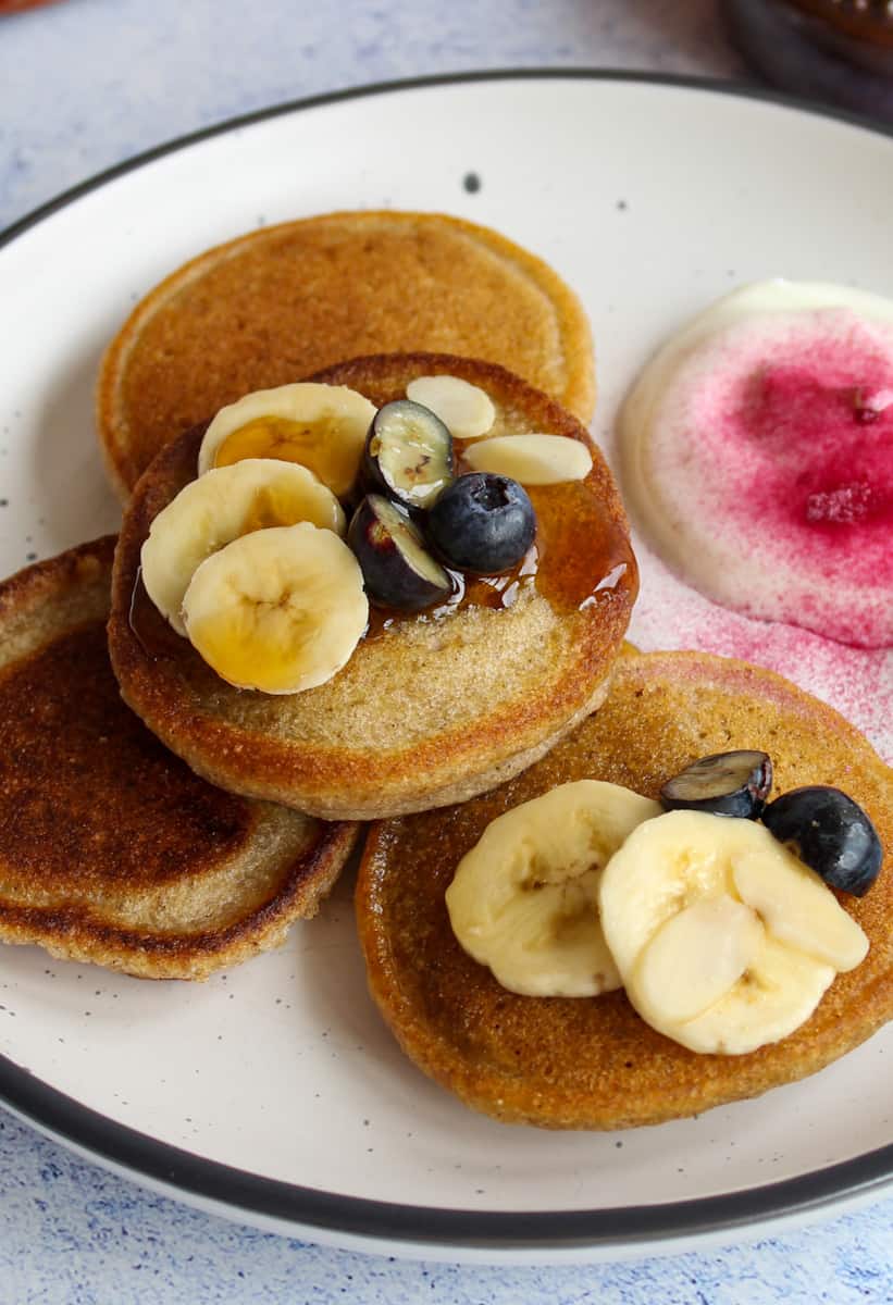 4 gluten-free almond pancakes on a plate with bananas and blueberries