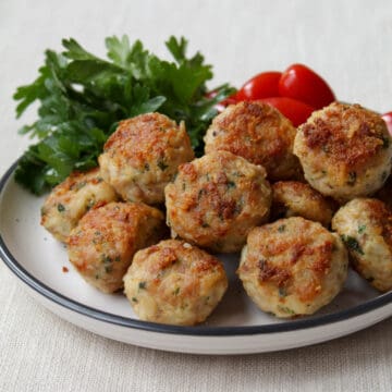 chicken meatballs on a plate with tomatoes and fresh parsley