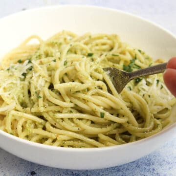 Spaghetti with pesto sauce in a white bowl
