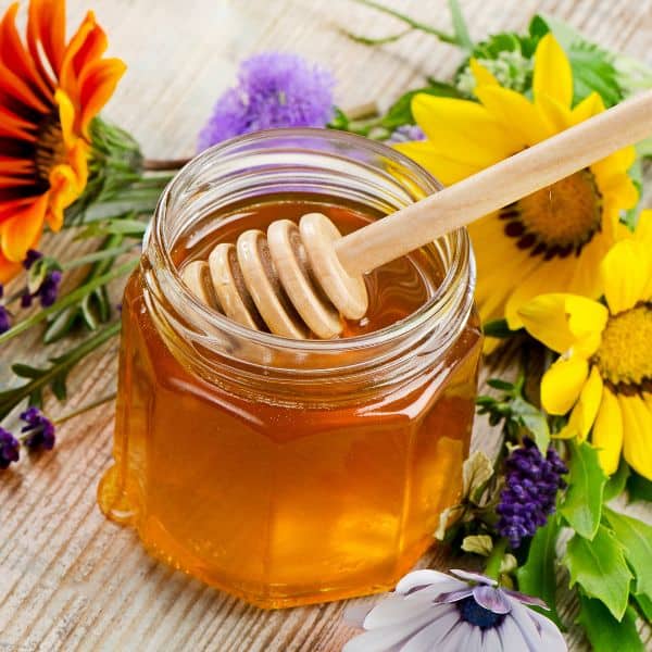 a glass jar with honey and flowers