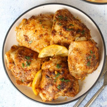 baked chicken thighs on a plate lemon slices