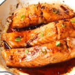 baked teriyaki salmon filets in a white frying pan.