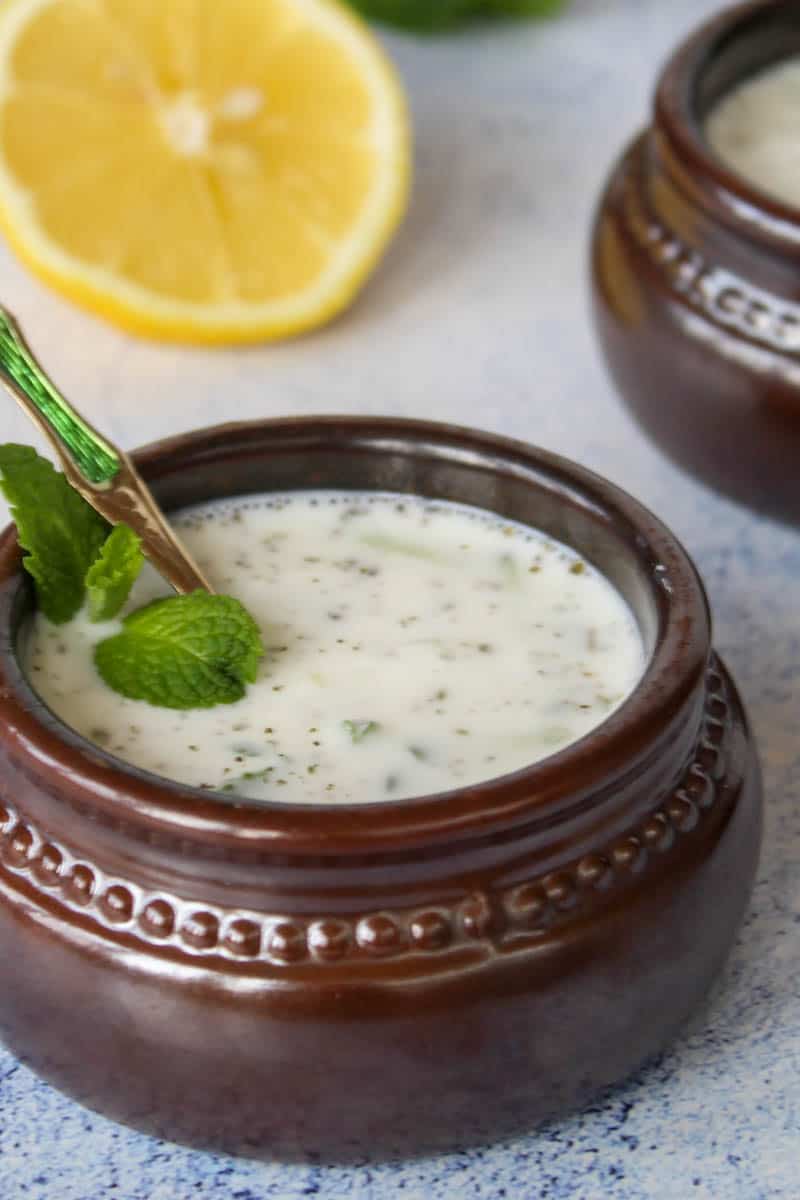 a bowl with cacik Turkish yogurt soup, served with mint and lemon