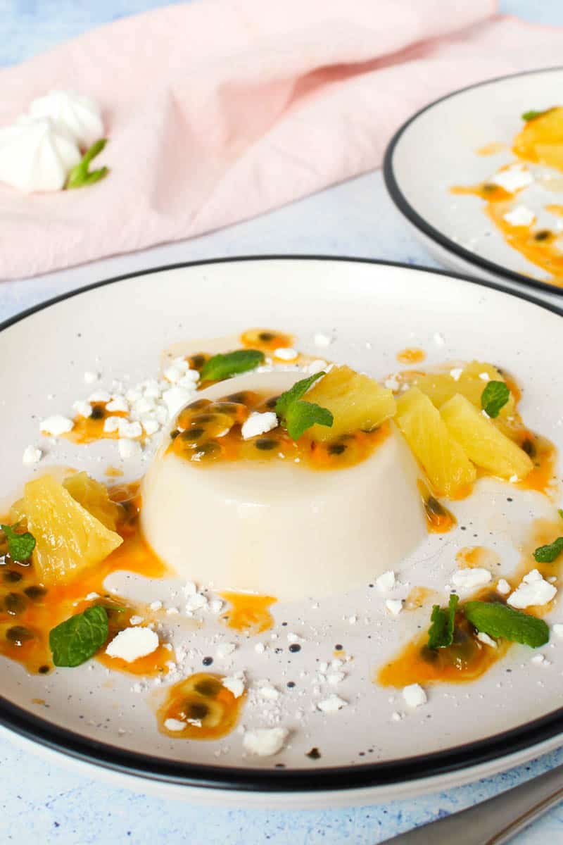 coconut panna cotta on a white plate sreved with tropical fruit