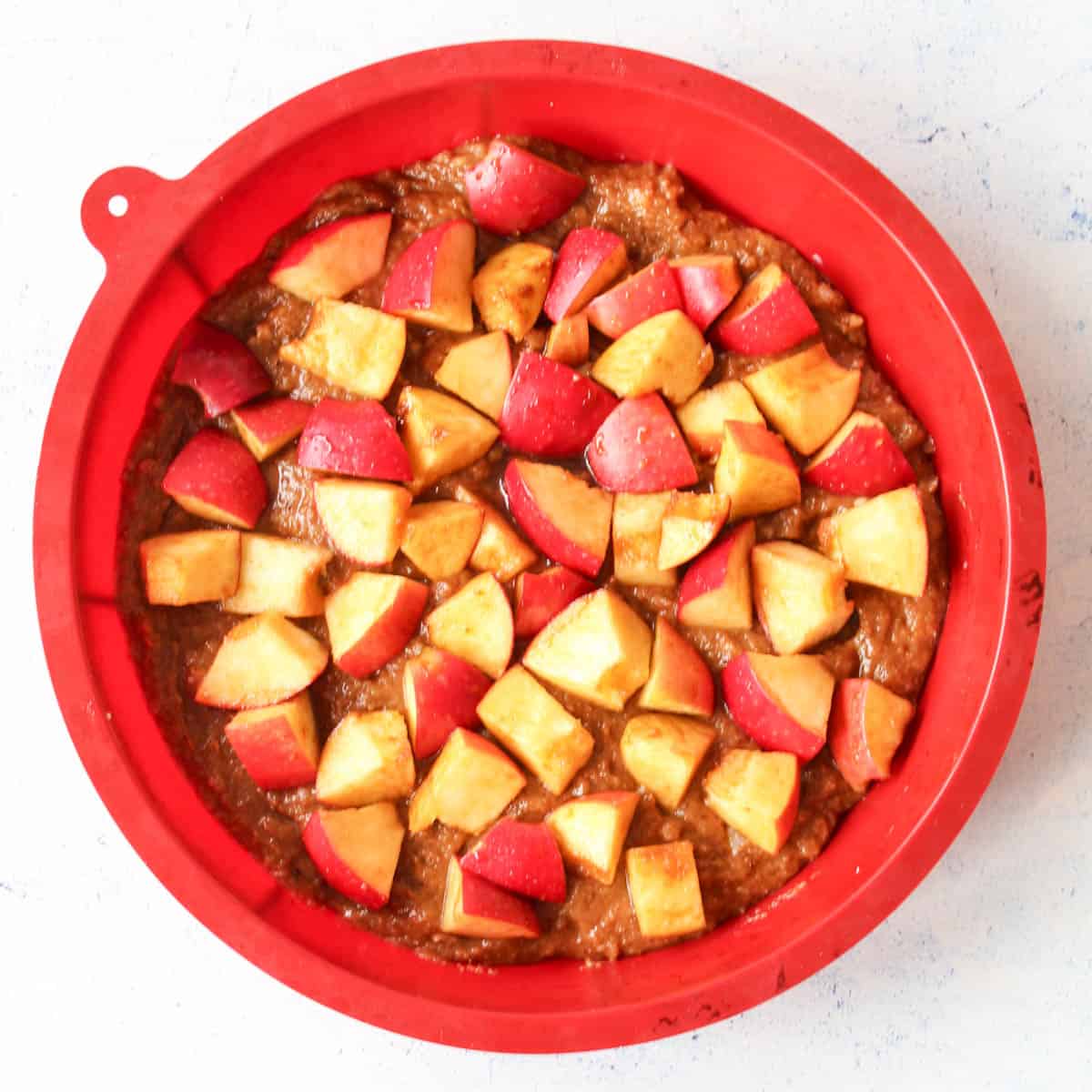 gluten-free apple cake in a red baking pan ready to be baked