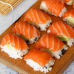 eight salmon nigiri on a wooden board
