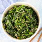 Japanese spinach salad gomae, served in a white bowl, sprinkled with sesame seeds.