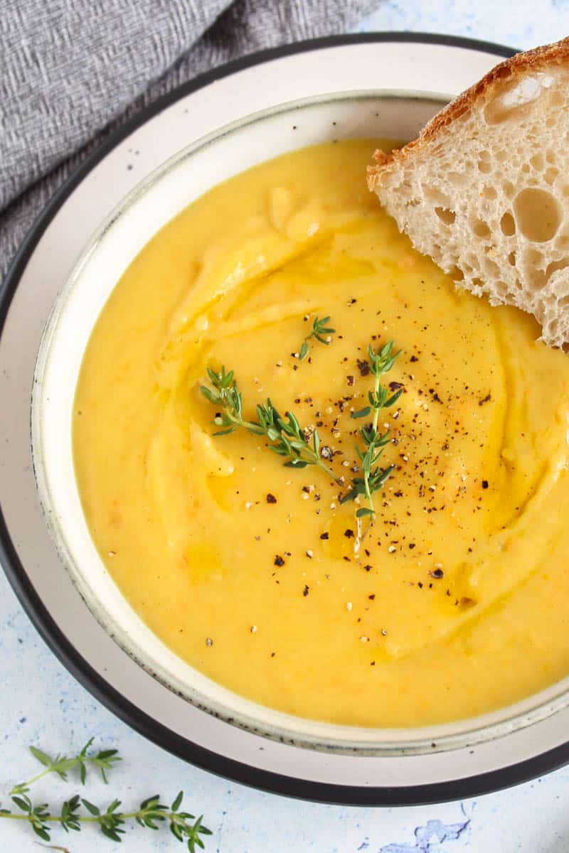 a bowl of tasty looking creamy soup with fresh thyme and slice of bread