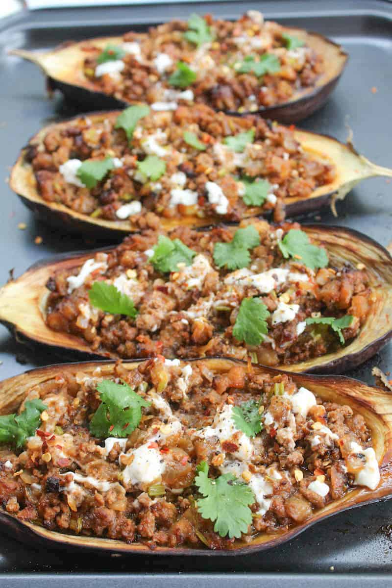4 baked eggplant halves stuffed with minced meat and yogurt on a baking tray 