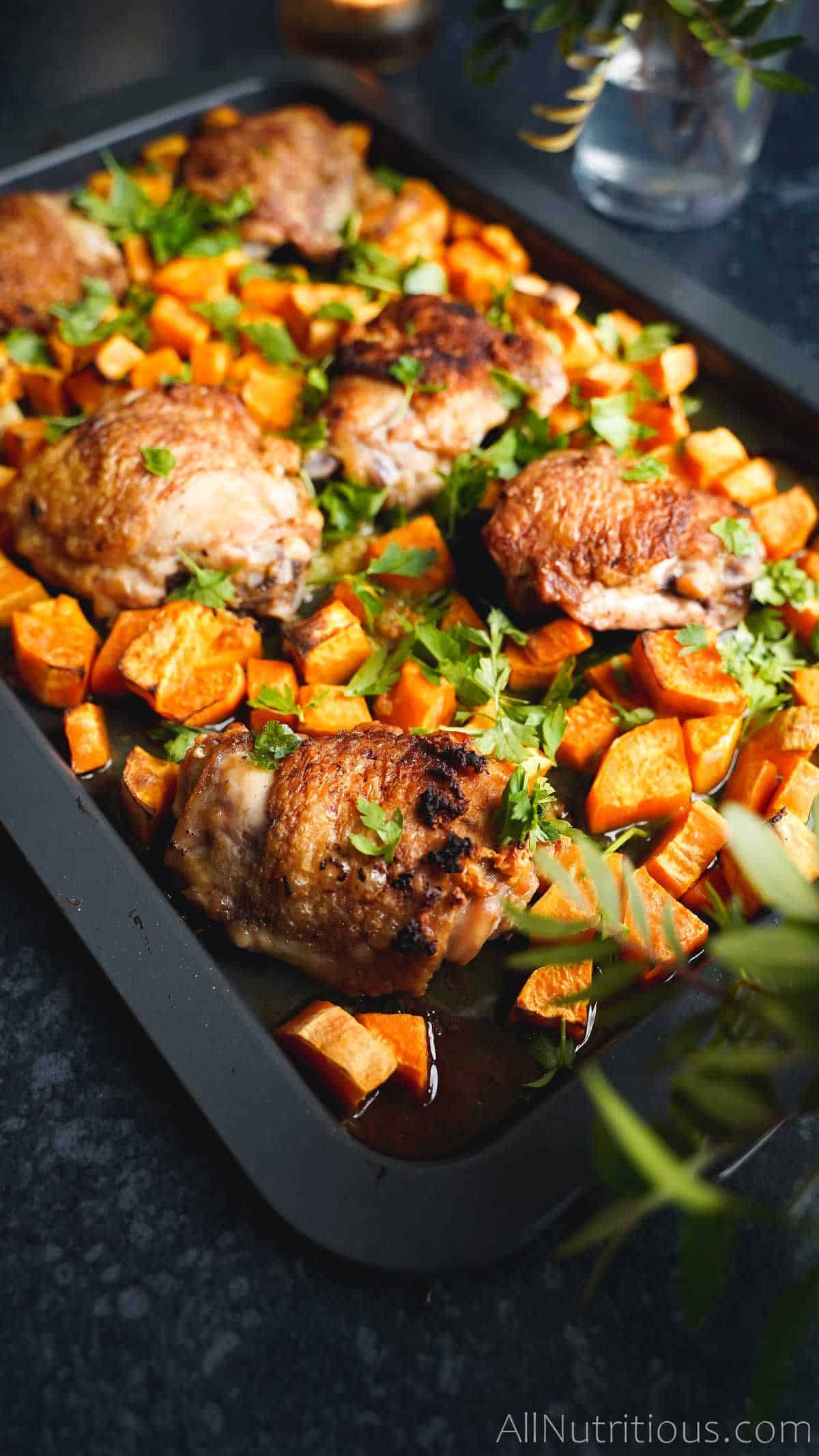 lemon chicken thighs with sweet potatoes on a baking tray