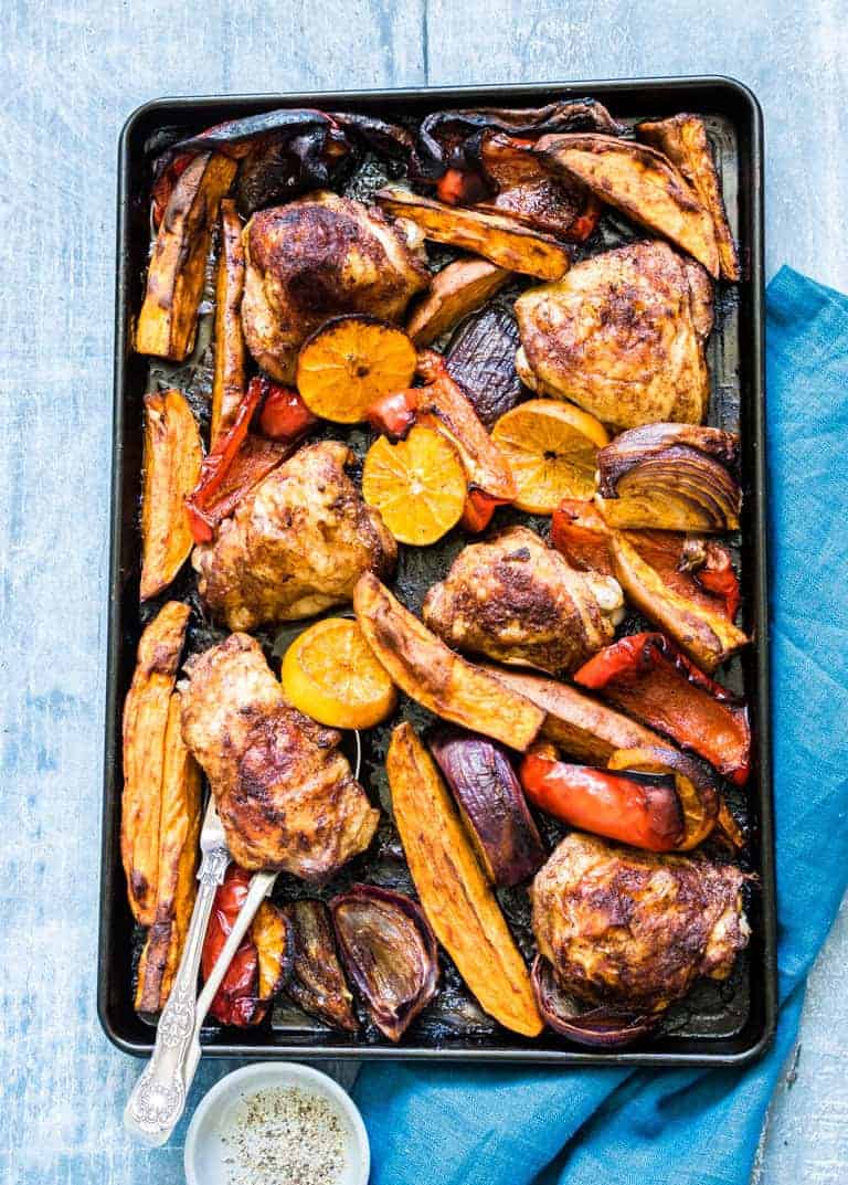 baked chicken thighs and sweet potato wedges on a baking tray