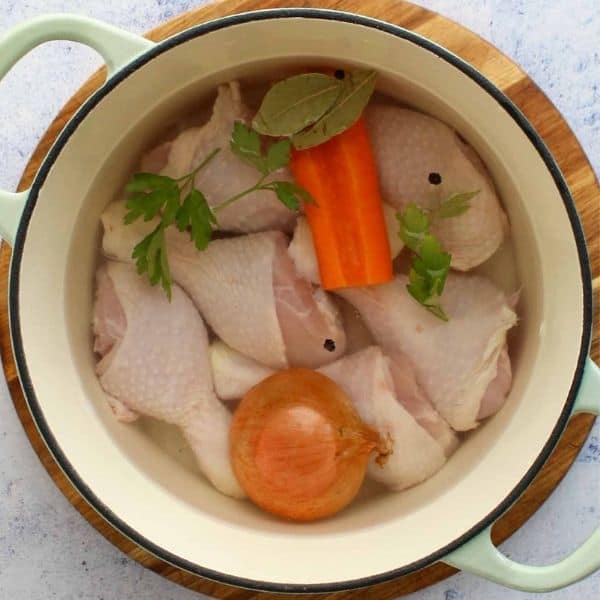 raw chicken legs in a dutch oven ready to be boiled