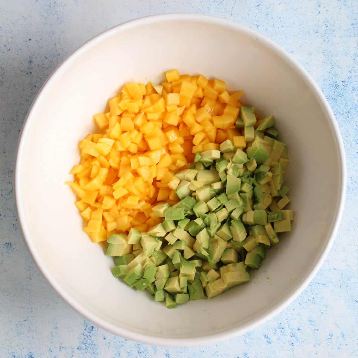 diced mango and avocado in a white bowl