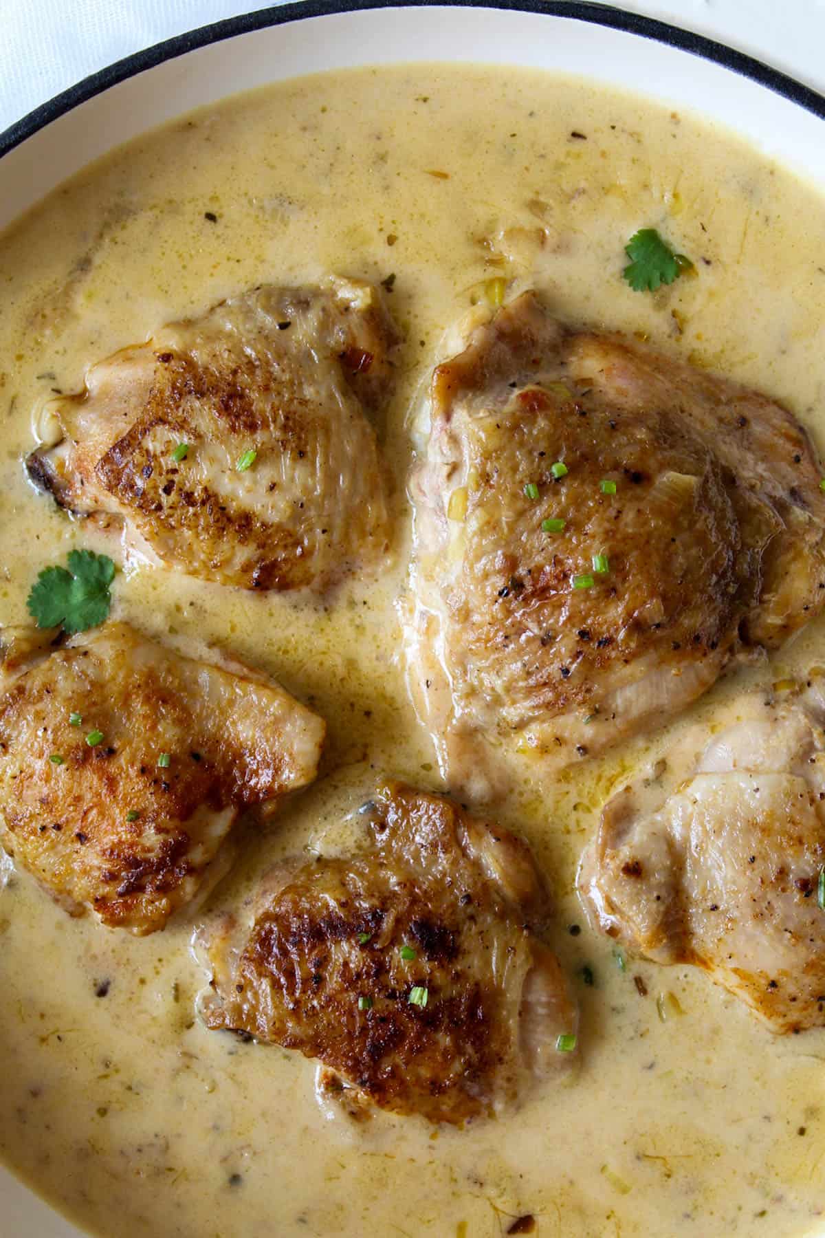 chicken thighs cooking in a creamy white sauce