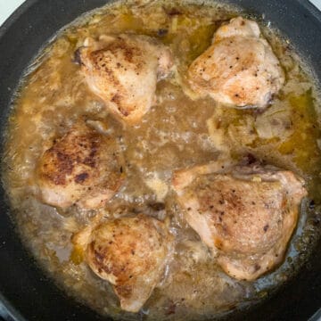 chicken thighs are simmering in creamy sauce
