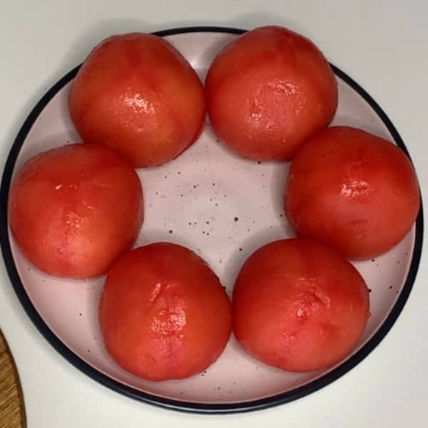 Six peeled tomatoes on a plate