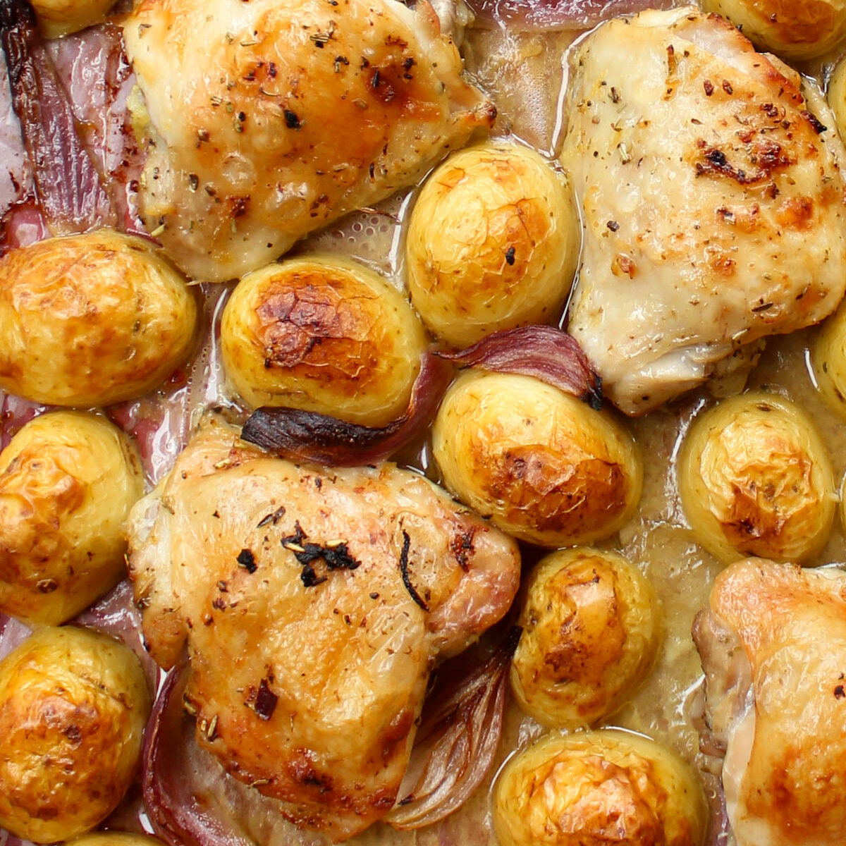 baked chicken and potatoes on a baking tray