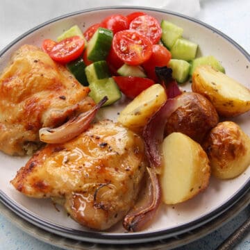 crispy Greek baked chicken thighs with golden baked potatoes and greek salad