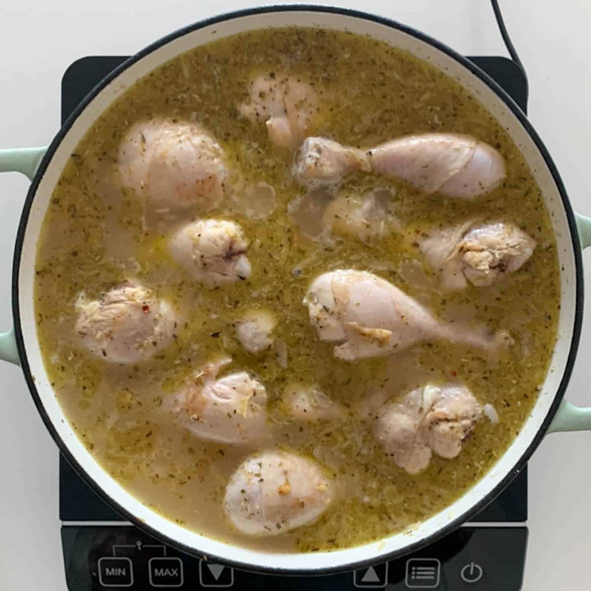 drumstick submerged in chicken stock in  a frying pan